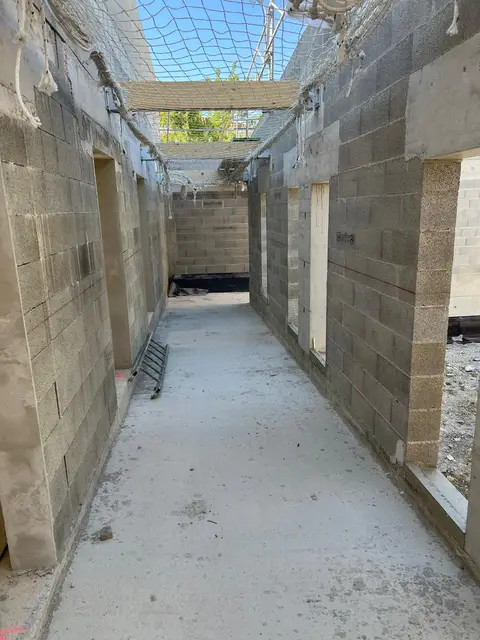 Filet de sécurité vu depuis l'intérieur du bâtiment, ses mailles projetant leur ombre sur la dalle