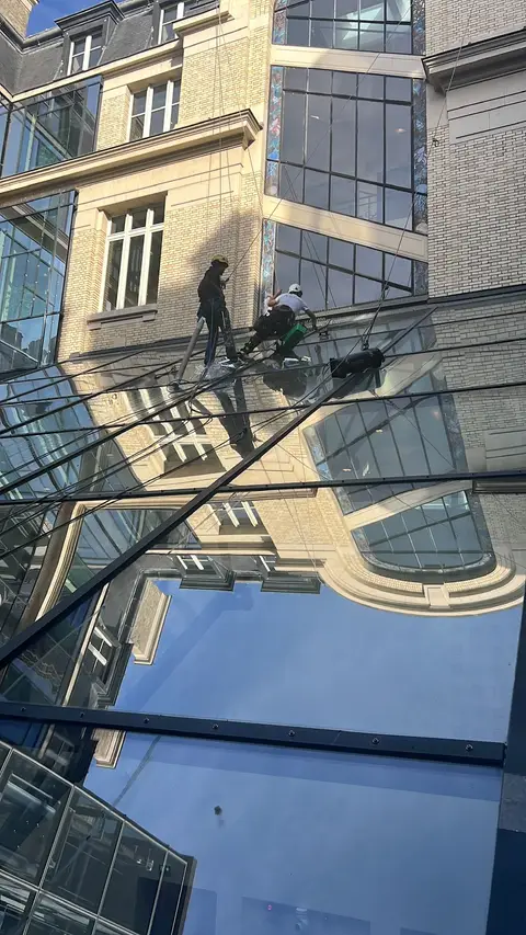 Deux cordistes en intervention de nettoyage sur une verrière et façade vitrée complexe