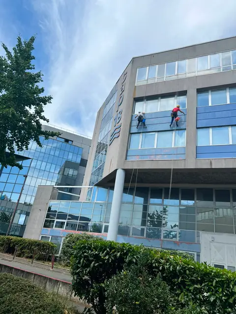 Deux cordistes effectuant le nettoyage des vitrages et du bardage d'un immeuble d'entreprise